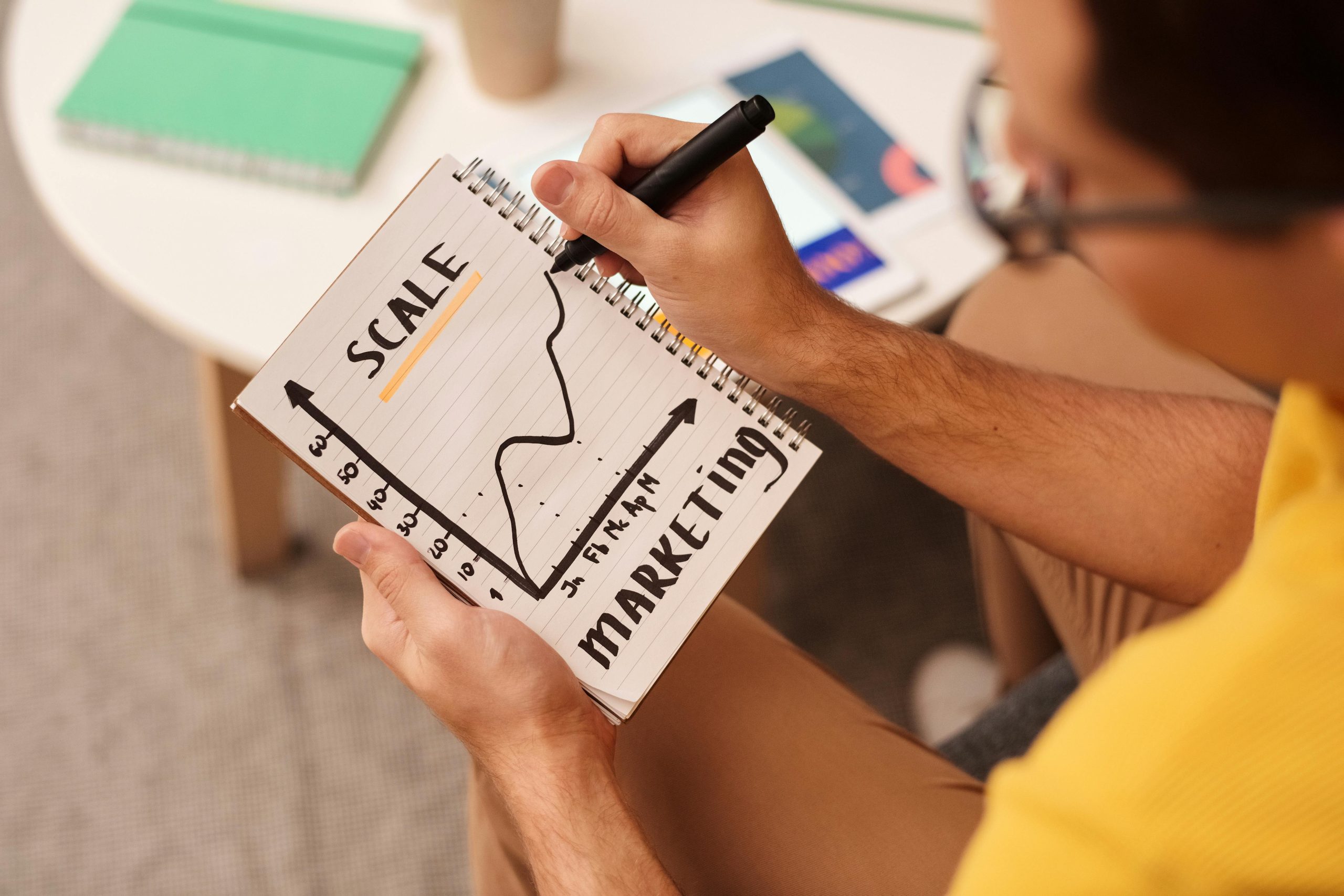 Scaling a Business Beyond Founder Dependency Person sketching a rising growth chart labelled scale and marketing, illustrating how businesses can transition from founder-led effort to scalable, compounding digital assets.