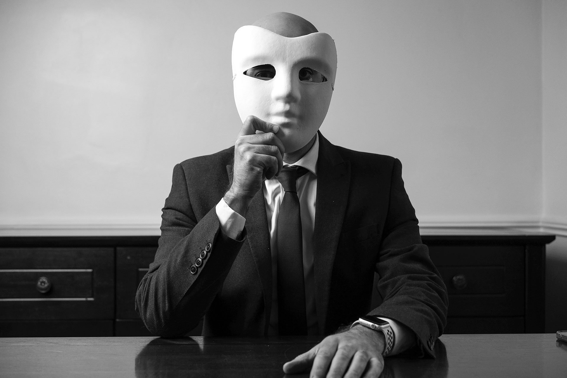Business professional wearing a blank mask while seated at a desk, symbolising faceless digital businesses that remove identity but may lack depth, differentiation, and long-term value.