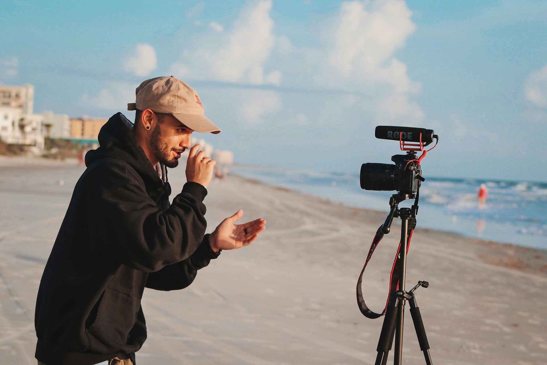 Content creator filming themselves on a camera by the beach, representing personal branding as a visibility tool that can drive early business growth but may not scale into a transferable asset.