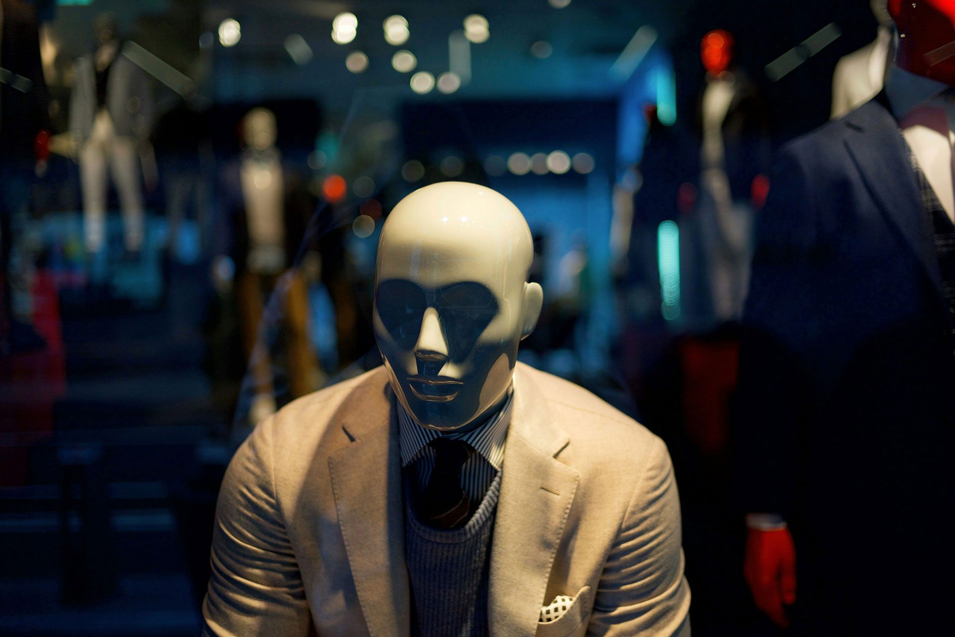 Faceless mannequin in a suit displayed among other mannequins, representing anonymous business models and the challenge of building recognisable, transferable value without a visible founder.